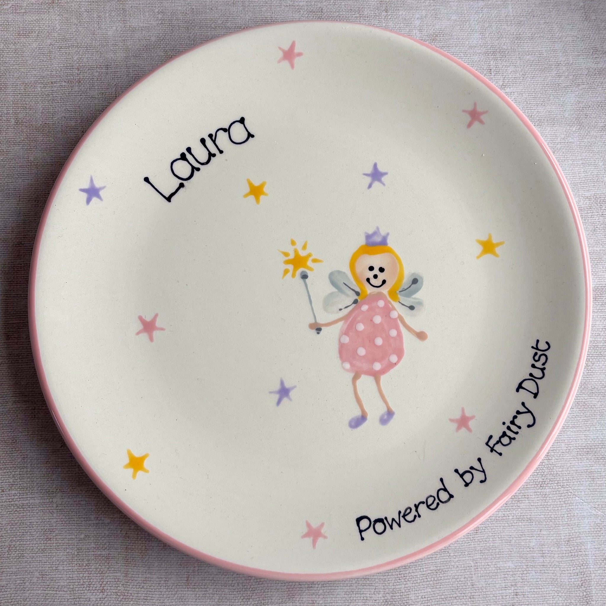 Children's plate with a fairy design and the name 'Laura' on a gray background